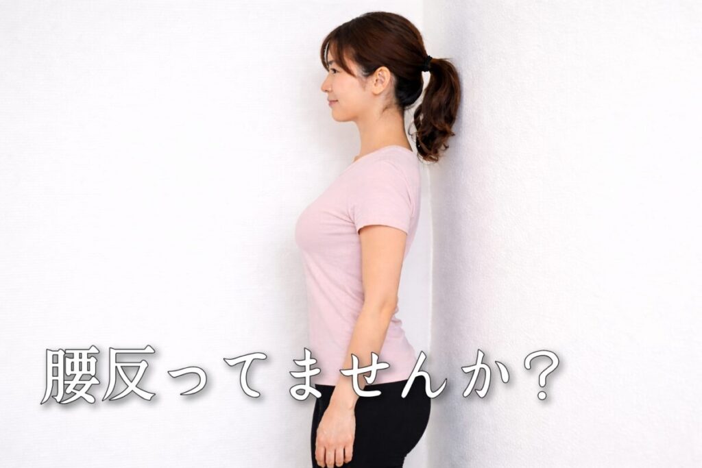 壁に立って反り腰かを確認する女性